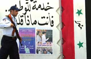 An Iraqi policeman passes election posters in the southern Iraqi town of Basra Tuesday Nov. 30, 2004. Iraqi Prime Minister Ayad Allawi will travel to Jordan on Tuesday to meet with Iraqis outside the country as part of attempts to get as many Iraqis as possible to participate in upcoming elections. (AP 