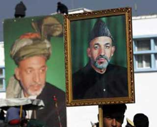 An Afghan boy holds a portrait of President Hamid Karzai during rehearsals for the upcoming inauguration in Kabul airport on December 5, 2004. A ring of steel was placed around the Afghan capital on Dec. 7 as Hamid Karzai prepared to be sworn in as the country's first popularly elected President at a ceremony attended by two of the figures most responsible for easing him into power.