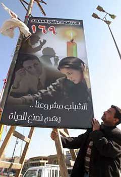 Iraqis hang a campaign poster advertising a list of candidates from the United Iraqi Alliance for the country's upcoming national elections in central Baghdad, Jan. 23, 2005. Al Qaeda ally Abu Musab al-Zarqawi declared a 'bitter war' on Iraq's parliamentary elections next Sunday, in an audio tape purporting to come from the Jordanian militant and posted on the Internet. [Reuters]