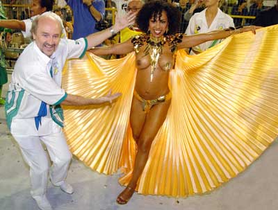 Well-known Samba dancer Valeria Valensa (R) is escorted by her husband Hans Donner during the parade by Academicos do Tucuruvi samba school in Sao Paulo, February 5, 2005. Brazilians of all walks of life sang and danced during the annual Carnival festivities. 