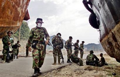 Indonesian soldiers take a break from patrolling the road from Banda Aceh to points on Aceh's west coast where the Indonesian Army has reported several firefights with rebels over the last few days including one involving an aid convoy Monday Feb. 21, 2005 in Leupung about 25 kilometers (15 miles) west of Banda Aceh. [AP]