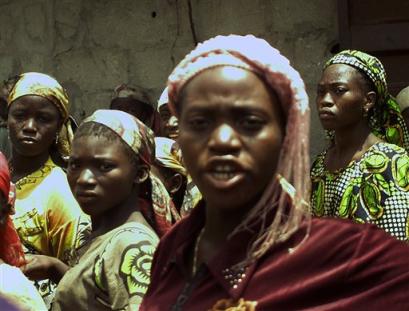 Woman and young girls who were among people that were found in a shipping container stand together in Lagos, Nigeria on Monday, March 7, 2005. Police found more than 60 children packed into a shipping container in Lagos, and a police spokesman said Monday it was believed they were to be sold as slaves or servants.(AP Photo/Sunday Alamba) 