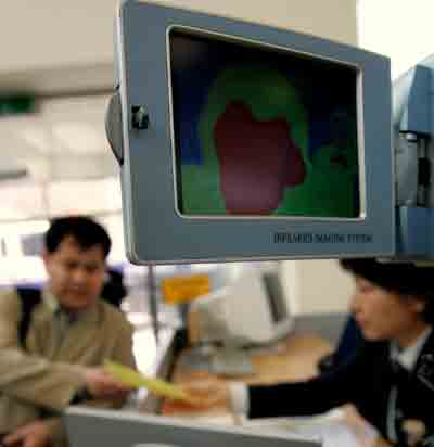 A South Korean worker (L), who works at the inter-Korean industrial complex in North Korea's Kaesong, passes a camera that monitors his temperature to check for possible bird flu infection at the Dorasan immigration office, near a demilitarised zone in Paju, about 55 km (34 miles) north of Seoul, April 22, 2005. [Reuters]