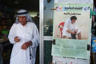  customer walks out from a general store past a copy of the Saturday edition of Iraq's Asharq al-Awsat newspaper, showing a picture of Saddam Hussein seated in a white robe which was originally used on Friday's front page of Britain's mass circulation tabloid newspaper the Sun, in central Baghdad, Iraq Saturday, May 21, 