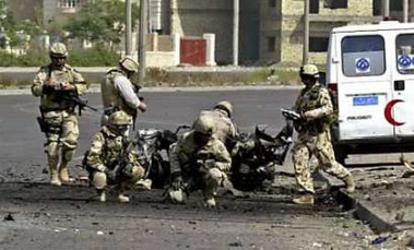 .S. soldiers search for clues at a car wreckage after a car bomb attack in Baghdad June 4, 2005.