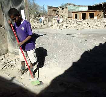 A Chilean boy sweeps a street in Huara town, some 96 km (59 miles) off Iquique, about 1,845 km (1,146 miles) north of Santiago, Chile, June 14, 2005. Boulders littered city streets and highways in northern Chile on Tuesday after a 7.9-magnitude quake caused landslides and wrecked homes, killing at least 11 and injuring 200. [Reuters]