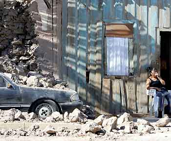 A woman sits outside her house in Huara town, some 96 km (59 miles) off Iquique, about 1,845km (1,146 miles) north of Santiago, Chile, June 14, 2005. [Reuters]