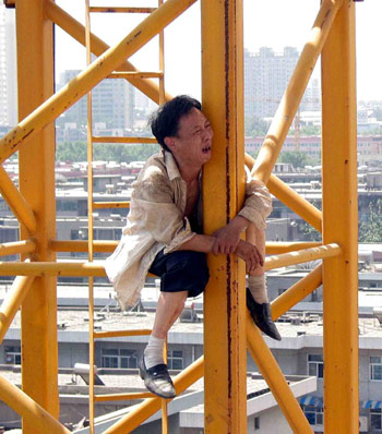 A man sits on a tower crane in a suicide attempt in Xi'an, Northwest China's Shaanxi Province July 11, 2005. The man surnamed Ding who is a restaurant owner in the city returned to the ground safely thanks to three hours's efforts by the local police. Why the man resorted to such an act is still unknown. [newsphoto]