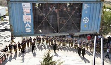 Jewish settlers and protesters are lowered to the ground inside a metal container from a rooftop where they were barricaded to resist evacuation of the Jewish settlement of Sanur, West Bank August 23, 2005. 