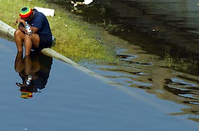 A woman bows her head as she sits in flood water during the aftermath of Hurricane Katrina in New Orleans, Louisiana September 3, 2005. 