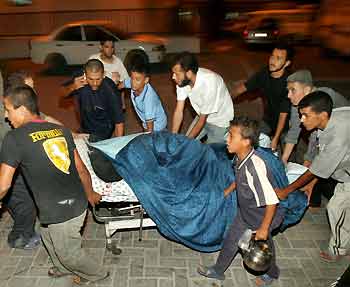 Palestinians carry a dead man after an explosion in Gaza September 5, 2005. A huge explosion on Monday destroyed three houses in a Gaza City suburb known as a Palestinian militant stronghold, killing three people and wounding more than 25, medics said. [Reuters]