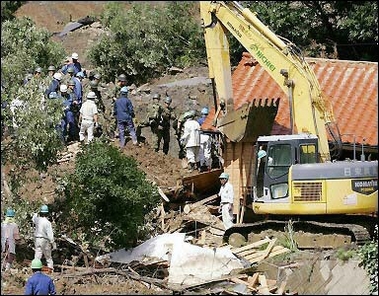 Rescue workers and self-defence soldiers work on a site where a landslide crushed a house in Iwakuni, western Japan.