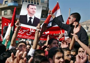 Syrians shout against the U.N. Mehlis report as they flash a poster showing Syrian President Bashar Assad Monday, Oct. 24, 2005, in Damscus, Syria. 