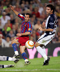 Ludovic Giuly (L) kicks the ball against Real Sociedad's player Javier Garrido before the second goal during their Spanish League soccer match at Nou Camp Stadium in Barcelona, Spain, October 30, 2005.