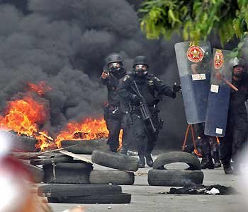 Philippine Special Weapons and Tactics (SWAT) members of the Philippine National Police and anti-riot policemen pass burning tyres put by protesters to block members of a demolition team at St. Joseph compound in Sun Valley, Paranaque city, south of Manila November 14, 2005.