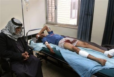 An unidentified father sits next to his injured policeman son at Al Kindi hospital in Baghdad, Iraq, Tuesday Dec. 6, 2005.