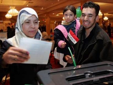 Iraqi expatriate Mushtak Al-Atiyah (R), 24 years old, holds his three-year old daughter Zanabi as he watches his mother Suzer (L) cast her absentee ballot in Iraq's election at a polling station in Dearborn, Michigan December 14, 2005. An estimated 240,000 Iraqi's in the U.S. are eligible to vote for Iraq's first parliament since the overthrow of Saddam Hussein in 2003. 