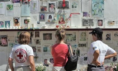 Unidentified women stops to reflect and look at fading photographs of Swedish victims of the Asian Tsunami Saturday, Dec. 24, 2005, at the wall of remembrance in Phuket, Thailand. More than 500 Swedes were killed when the killer waves struck Thailand's beaches on Dec. 26, 2004.