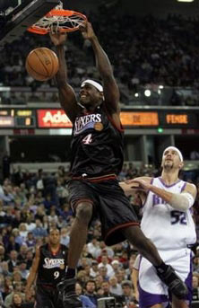 Philadelphia 76ers forward Chris Webber, center, hangs on the rim after scoring over Sacramento Kings center Brad Miller during the first quarter of NBA basketball action in Sacramento, Calif., Tuesday, Jan. 3, 2006. 