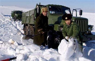 Chinese soldiers clear snow around a stranded truck in northwest China's Xinjiang Uygur Autonomous Region, January 5, 2006. 