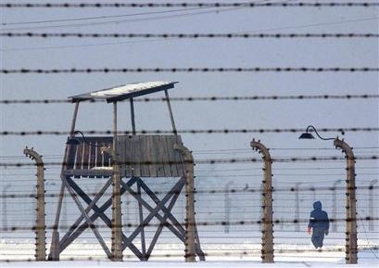 A person walks past a guard tower at the former Nazi-run Auschwitz-Birkenau concentration camp in Brzezinka, Poland, on Friday, Jan. 27, 2006. 