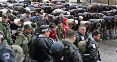 Israeli policemen watch as Palestinians pray on the street near Al-Aqsa compound in Jerusalem's Old city February 3, 2006. 