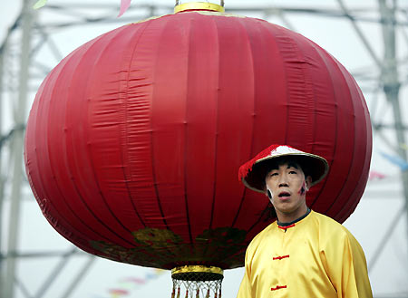 A Chinese performer dances beside a giant red lantern during a Lantern Festival activity in Beijing February 12, 2006. Lantern Festival marks the last day of the 15-day long Spring Festival, the most important festival of the year in China. [Reuters]