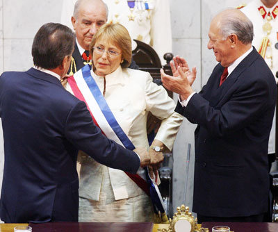 Chile's new President Michelle Bachelet receives the presidential sash from the President of the Senate Eduardo Frei (L) while outgoing president Ricardo Lagos (R) applauds in Valparaiso, Chile, March 11, 2006. Bachelet, who became Chile's first woman president, was taken political prisoner by the military regime in the 1970s and captivated Chileans in a role that symbolized reconciliation at long last between the country's deeply polarized right and left.