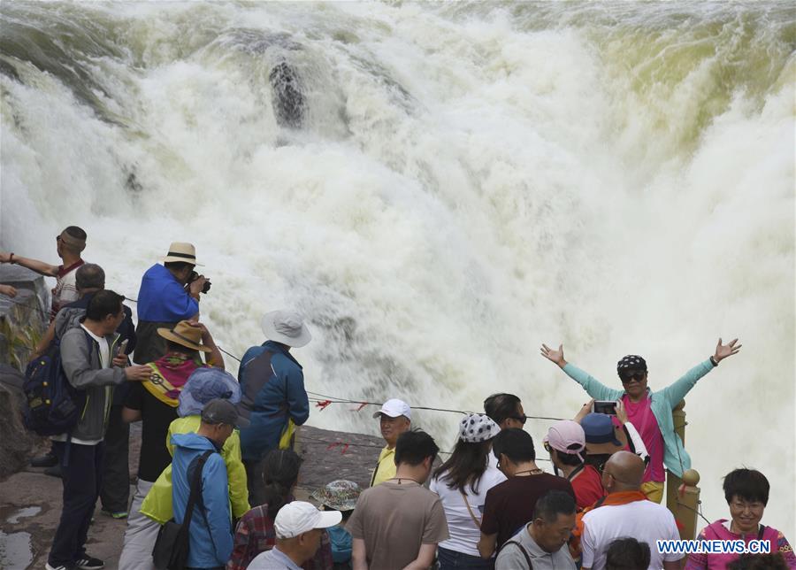 Visitors view Hukou Waterfall in N China