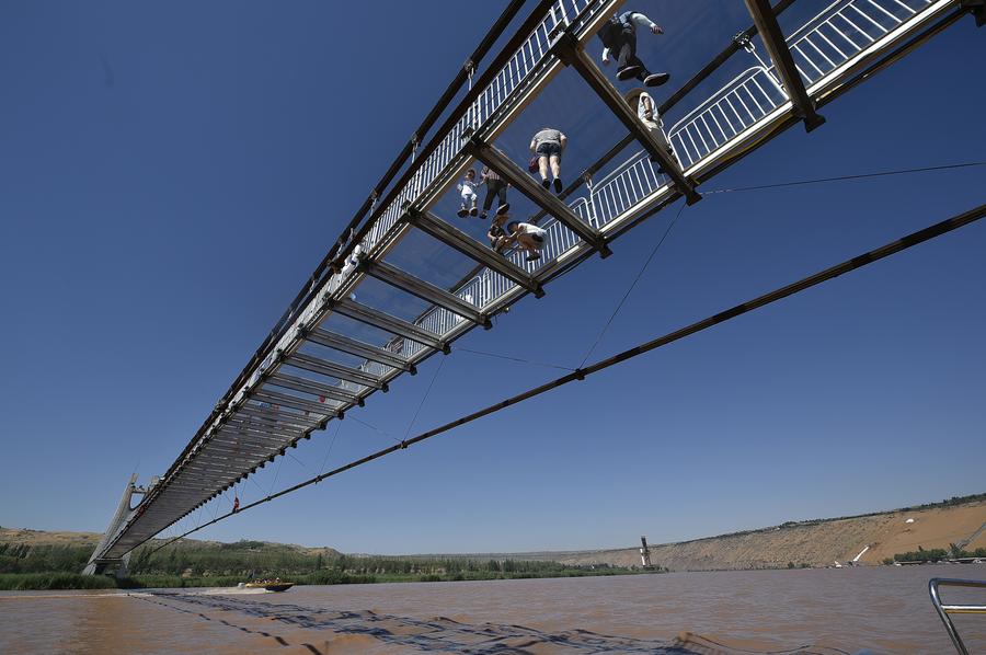 Tourists walk on glass bridge across Yellow River in Ningxia