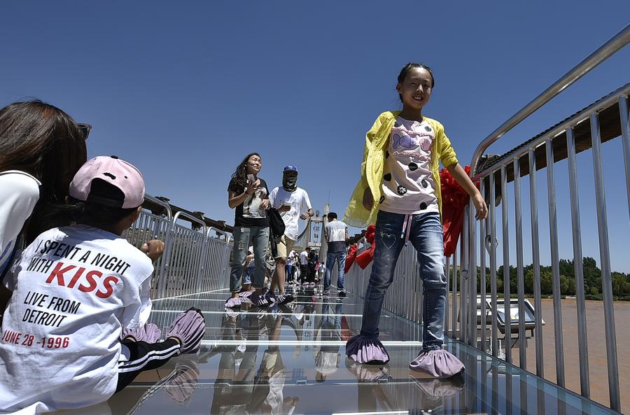 Tourists walk on glass bridge across Yellow River in Ningxia