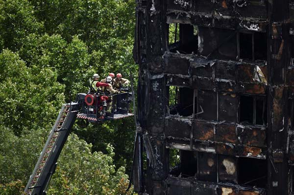 UK Prime Minister weathers criticism as Grenfell fire death toll rises to 30